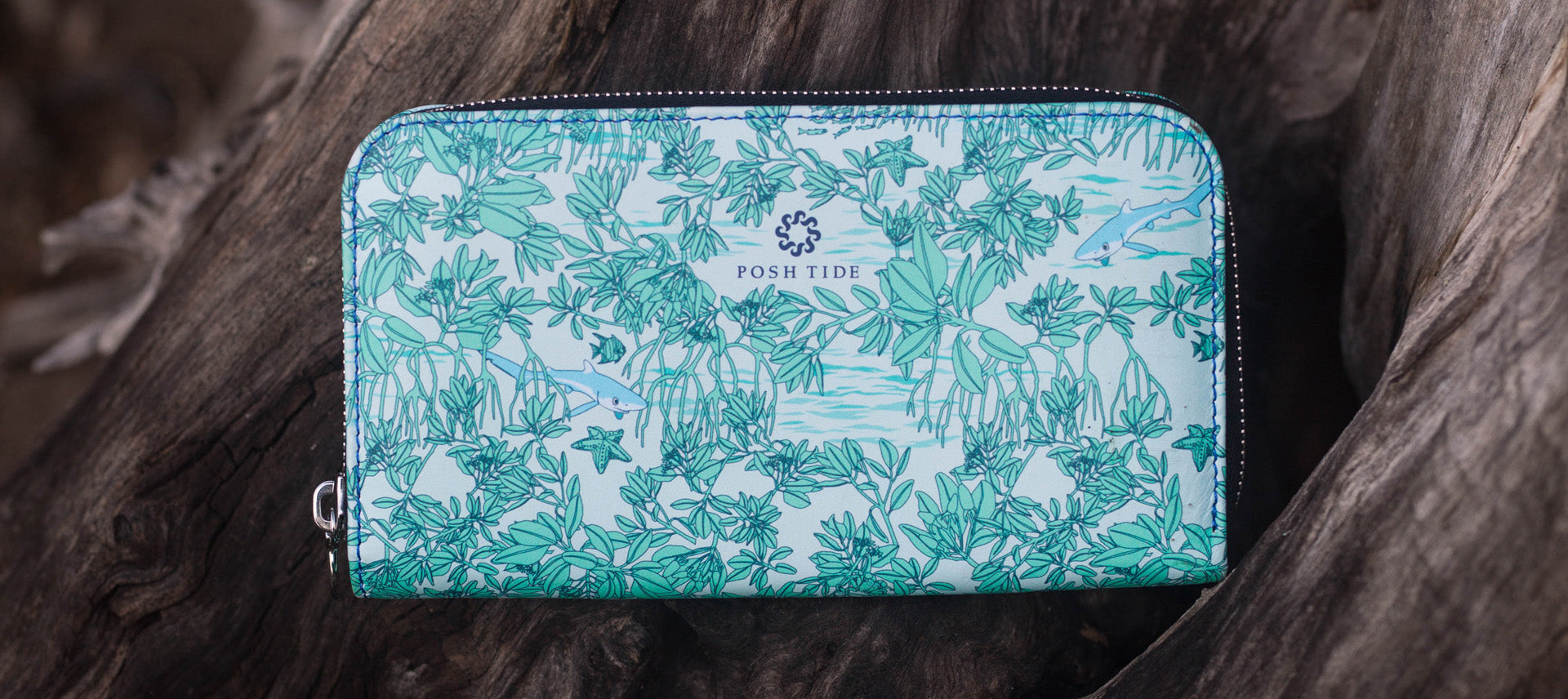 close up view of Posh Tide's leather zip around long wallet with illustrations of mangroves in blue.