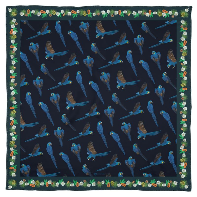 The hyacinth macaw is sometimes called the gentile giant of parrots, even though it the largest parrot of South America and can easily crack a coconut in its beak! This lovely square Georgette silk scarf honors this remarkable parrot with vibrant blue feathers, and the delicate ecosystem of fruits and nuts it loves to feed on. The deep green border is decorated with palm and Brazil nuts, papayas, and flowers. While the lush dark blue center square shows many parrots flying.